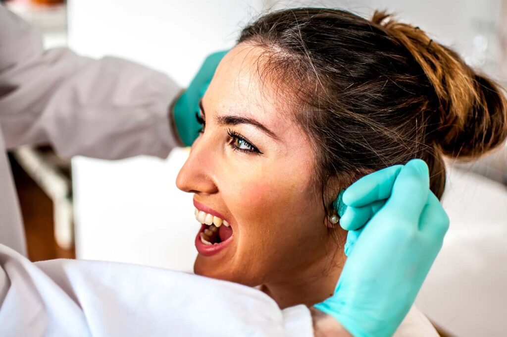 Woman with TMD symptoms in orthodontist office being evaluated for TMJ disorders