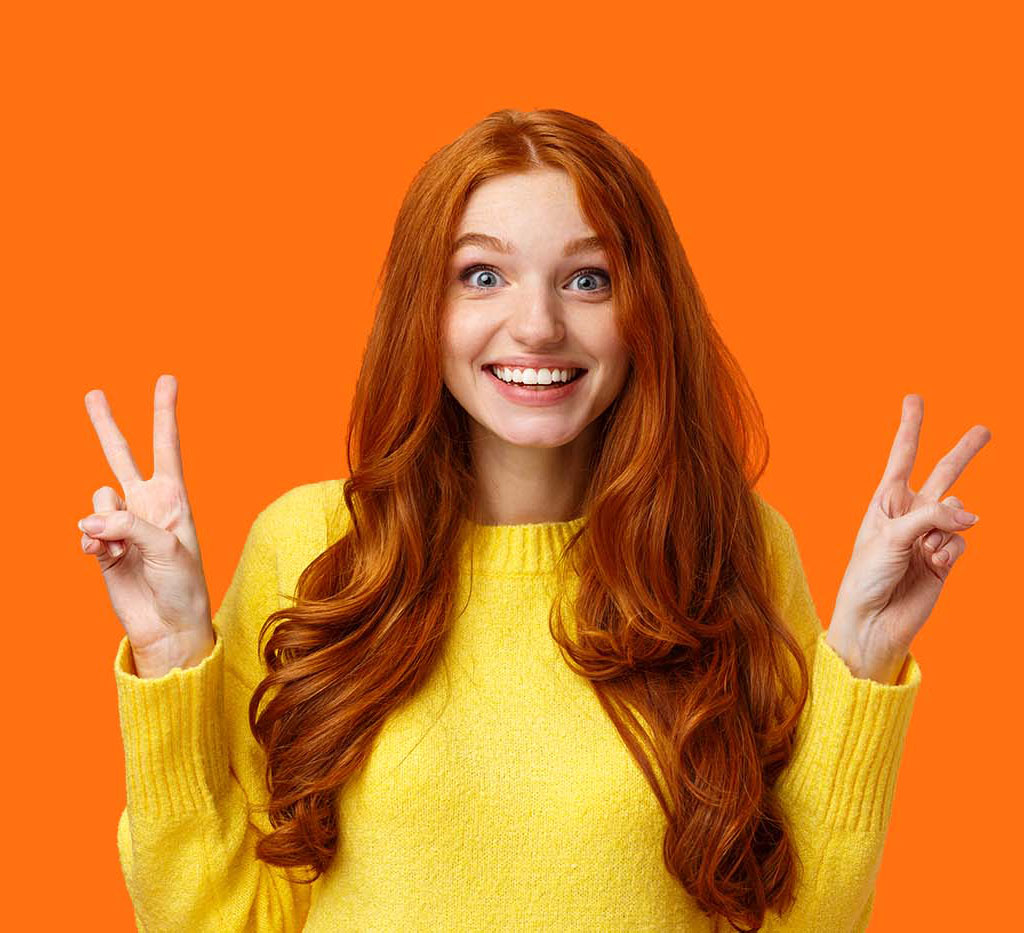 cheerful teen girl giving peace sign showing off her beautiful smile after straightening her teeth in front of orange background